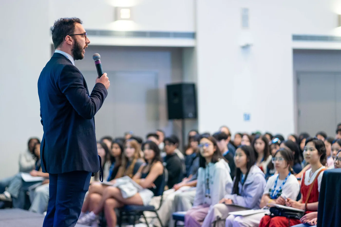Alan speaking with a microphone to a large audience of students